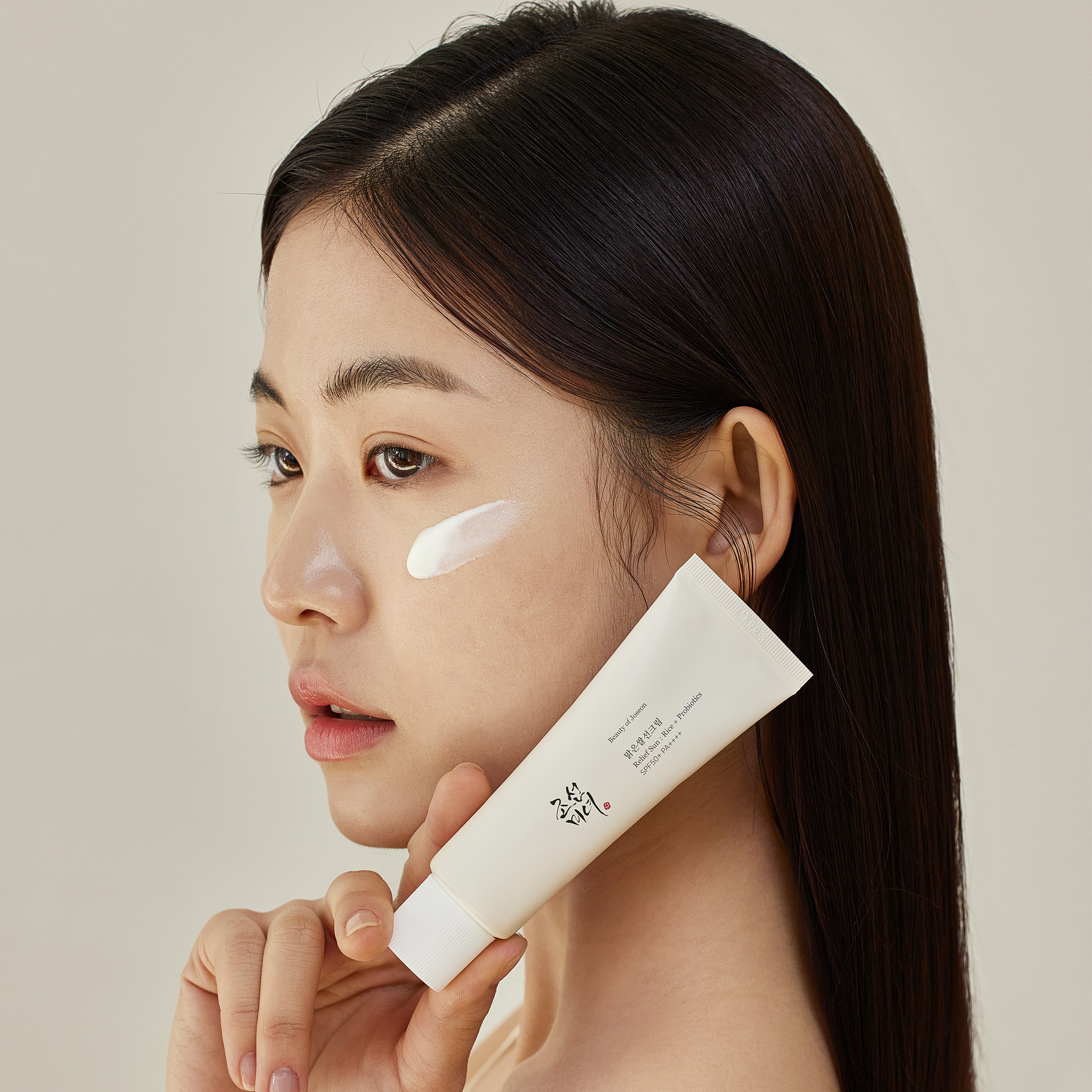 Model holding Beauty of Joseon Relief Sun : Rice + Probiotics (SPF50+ PA++++) 50ml to display beside her face